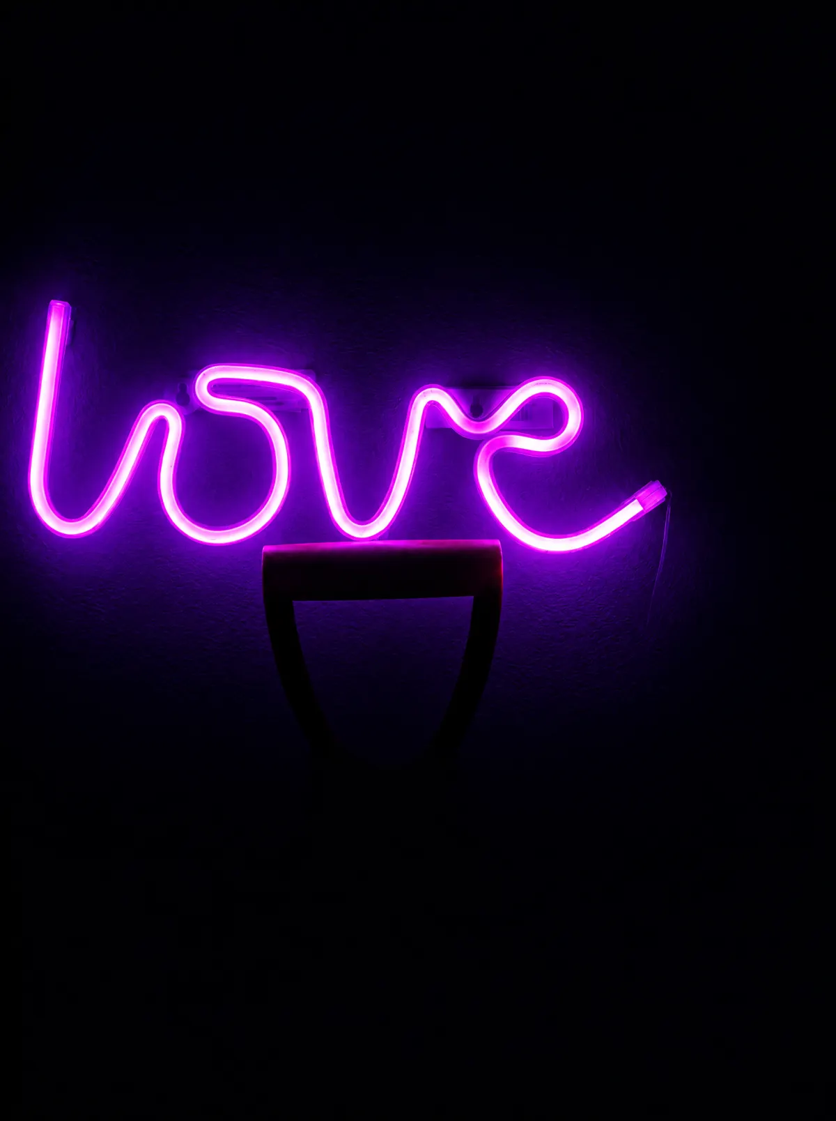 Розовая неоновая надпись «love» на стене